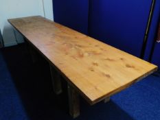 A large pine table top set on crude stand, 130in w