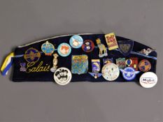 A cap with a quantity of vintage badges including