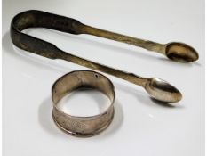 A pair of silver tongs twinned with a silver napki