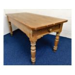 An antique farmhouse kitchen table with drawer at