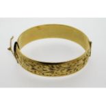 A 9ct gold metal core bangle, safety chain a/f, in