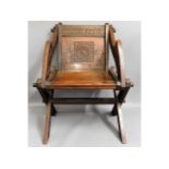 An oak Glastonbury chair with carved decor & scrip