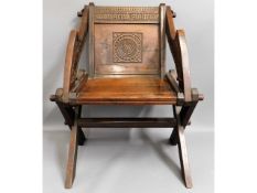 An oak Glastonbury chair with carved decor & scrip