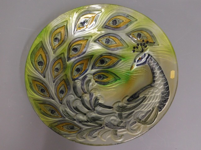 A large decorative glass dish with peacock feather