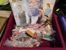 A lined box containing knitting needles & patterns