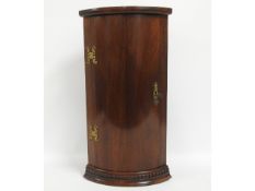 A small wall mounted mahogany corner cupboard with