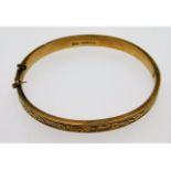 A 9ct gold bangle with carved decor, lacks safety