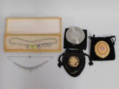 Three compacts twinned with two costume necklaces