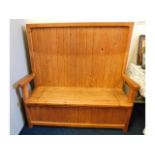 A pine high backed settle with storage under seat,