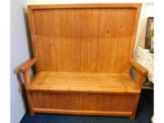 A pine high backed settle with storage under seat,