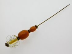 A Victorian amber hat pin on yellow metal pin, 130