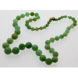 An antique jade necklace with yellow metal clasp,