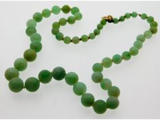 An antique jade necklace with yellow metal clasp,