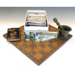 Carved wooden chessboard, together with a bronze pestle and mortar, postcards, etc