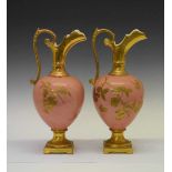 Pair of pink ground gilded ceramic ewers