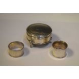 George V silver circular lidded dressing table box, plus two silver napkin rings