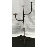 A wrought iron three arm candlestick 113cm tall.