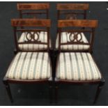 Set of four mahogany dining chairs with beige and green striped upholstered seat pads.