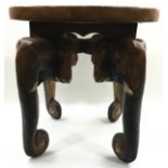 Carved wooden circular side table on four legs in the form of elephant heads. 50cm tall x 50cm