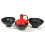 A West German lava single handled jug together with a pair of black serving bowls with makers marks.