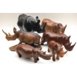 Collection of carved wooden rhinoceroses, 6 in all, the largest being 27cm across x 18cm tall