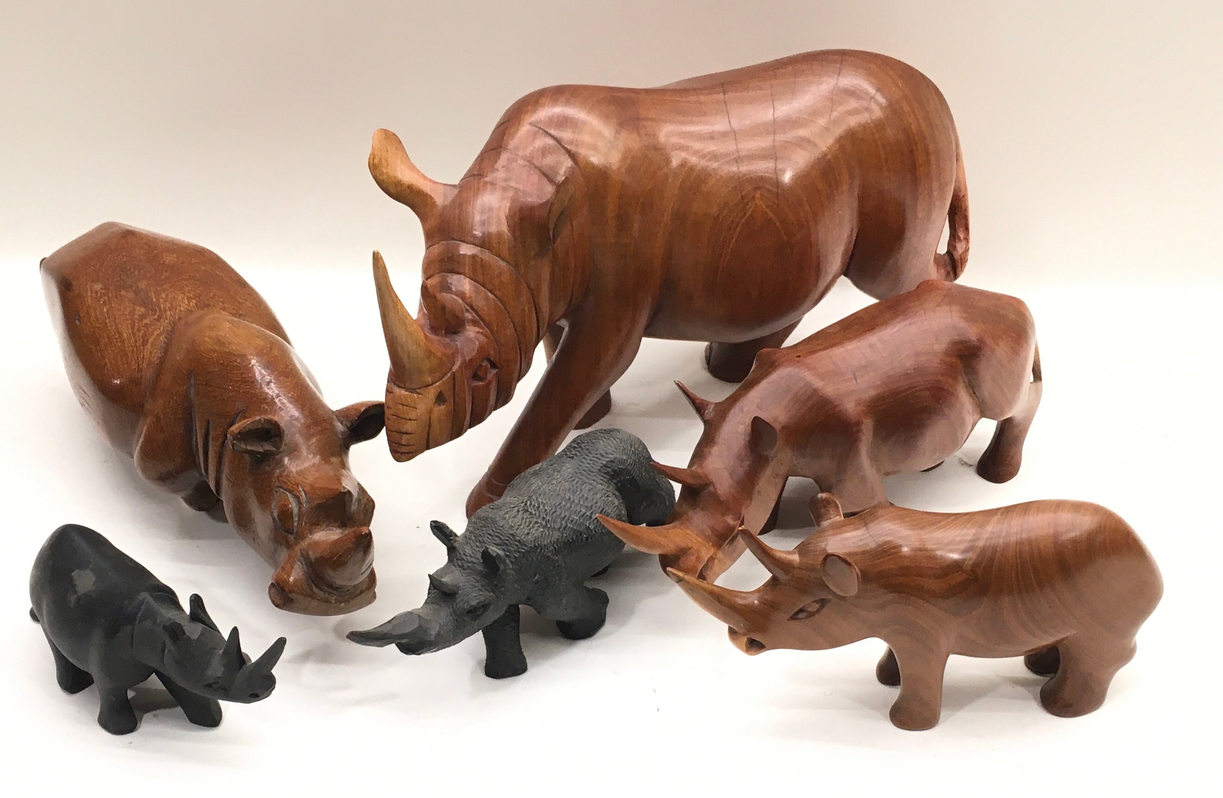 Collection of carved wooden rhinoceroses, 6 in all, the largest being 38cm across x 21cm tall