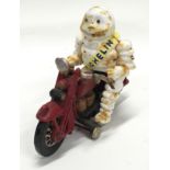 A vintage Michelin Man riding a motor bike.