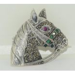 A silver horse brooch pendant set with ruby eye and emerald nose band.