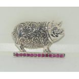 A silver pig brooch with ruby Platform.