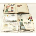 A green strand stamp album containing a collection of worldwide stamps and various first day covers.