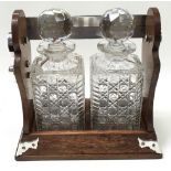 A Victorian oak & silver plated Tantalus with two cut glass decanters.