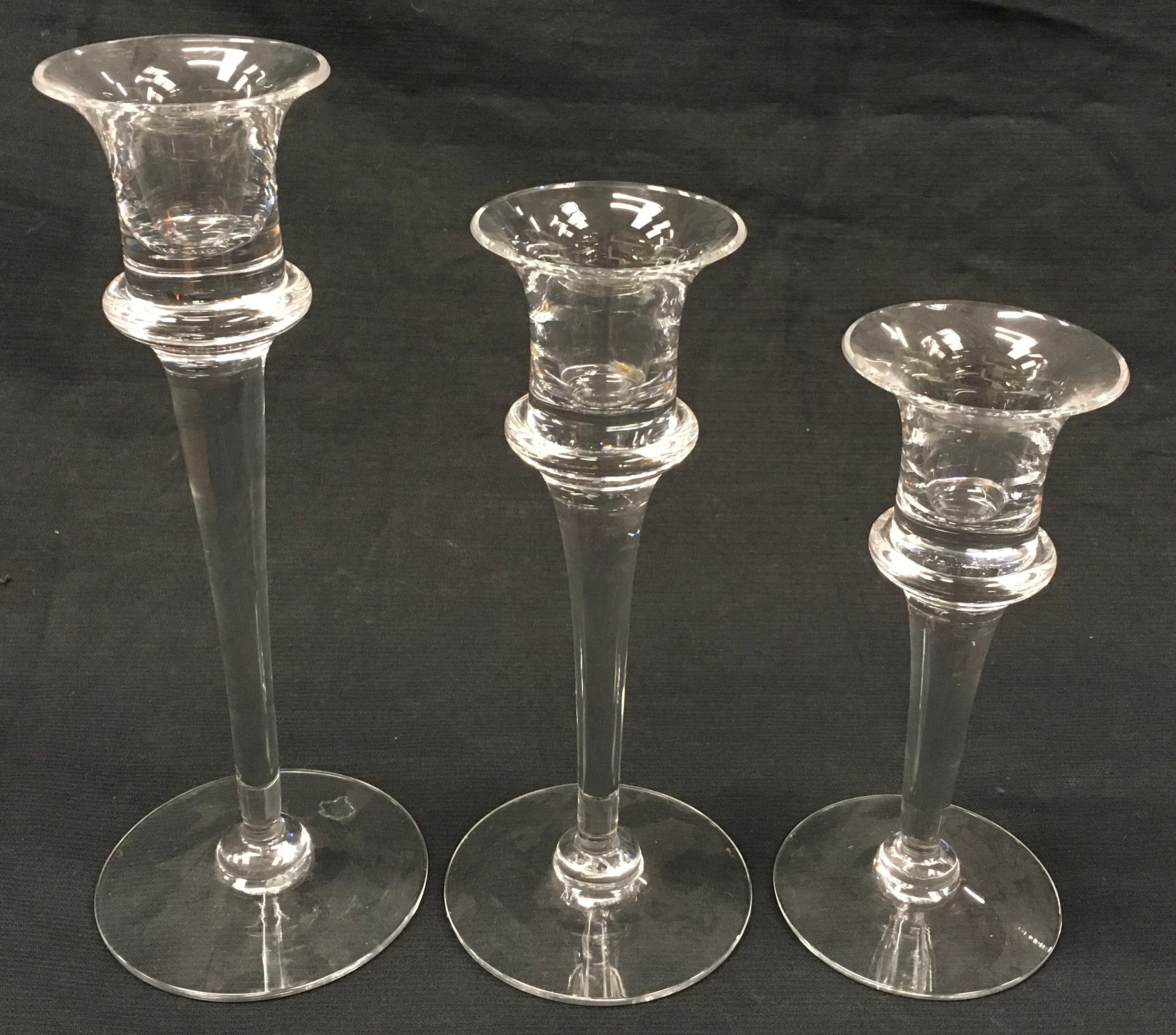 Three graduated Dartington glass candlestick holders the largest being 24cm tall.