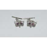A pair of owl cuff links with ruby eyes.