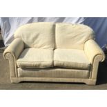 Two seater cream upholstered settee. 155x93cms. Seat height 42cms.