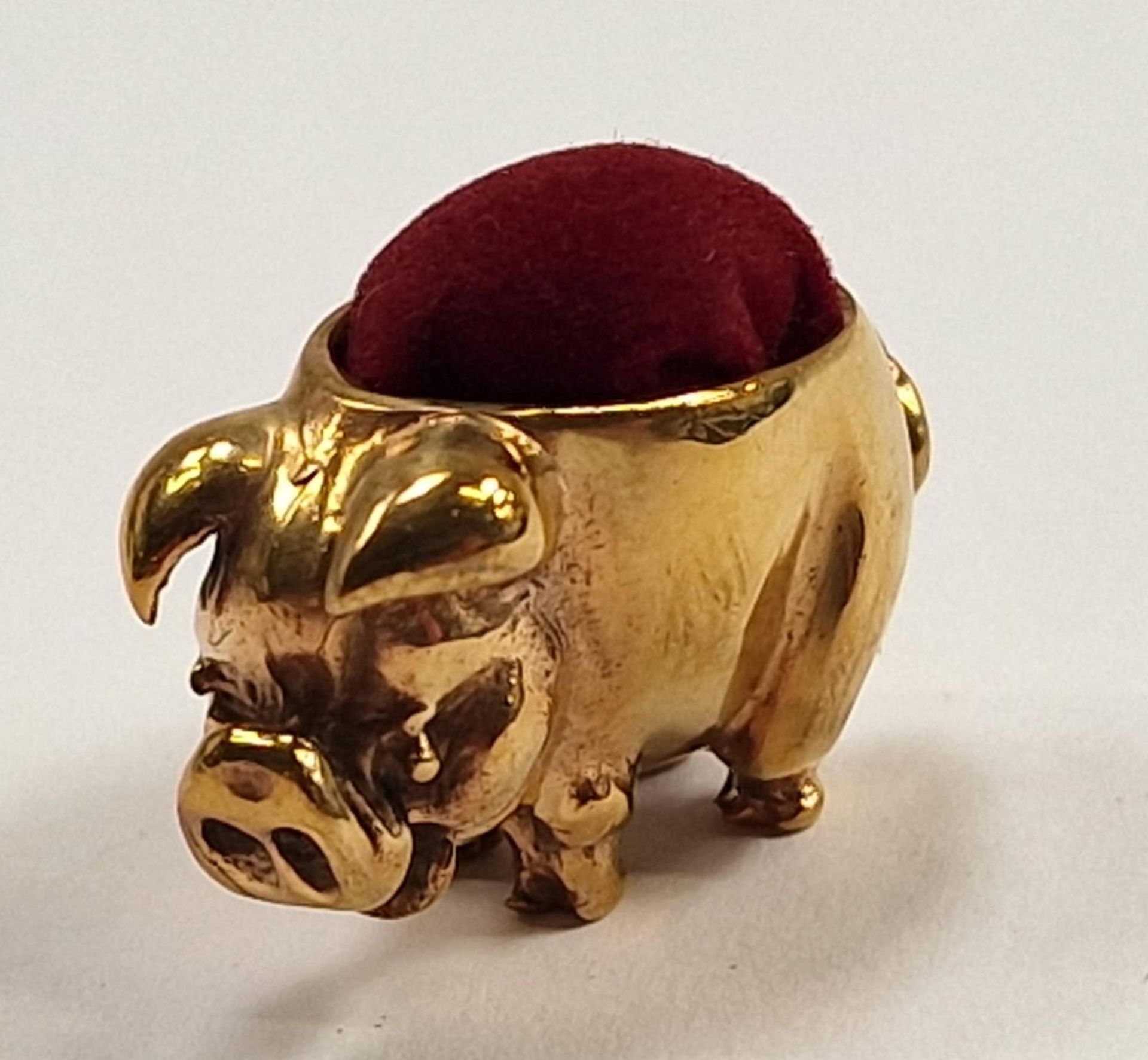 A brass pig pincushion