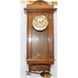 Oak cased chiming wall clock with pendulum and key. Seen working