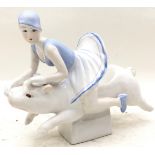 A ceramic figure of a lady riding a pig.