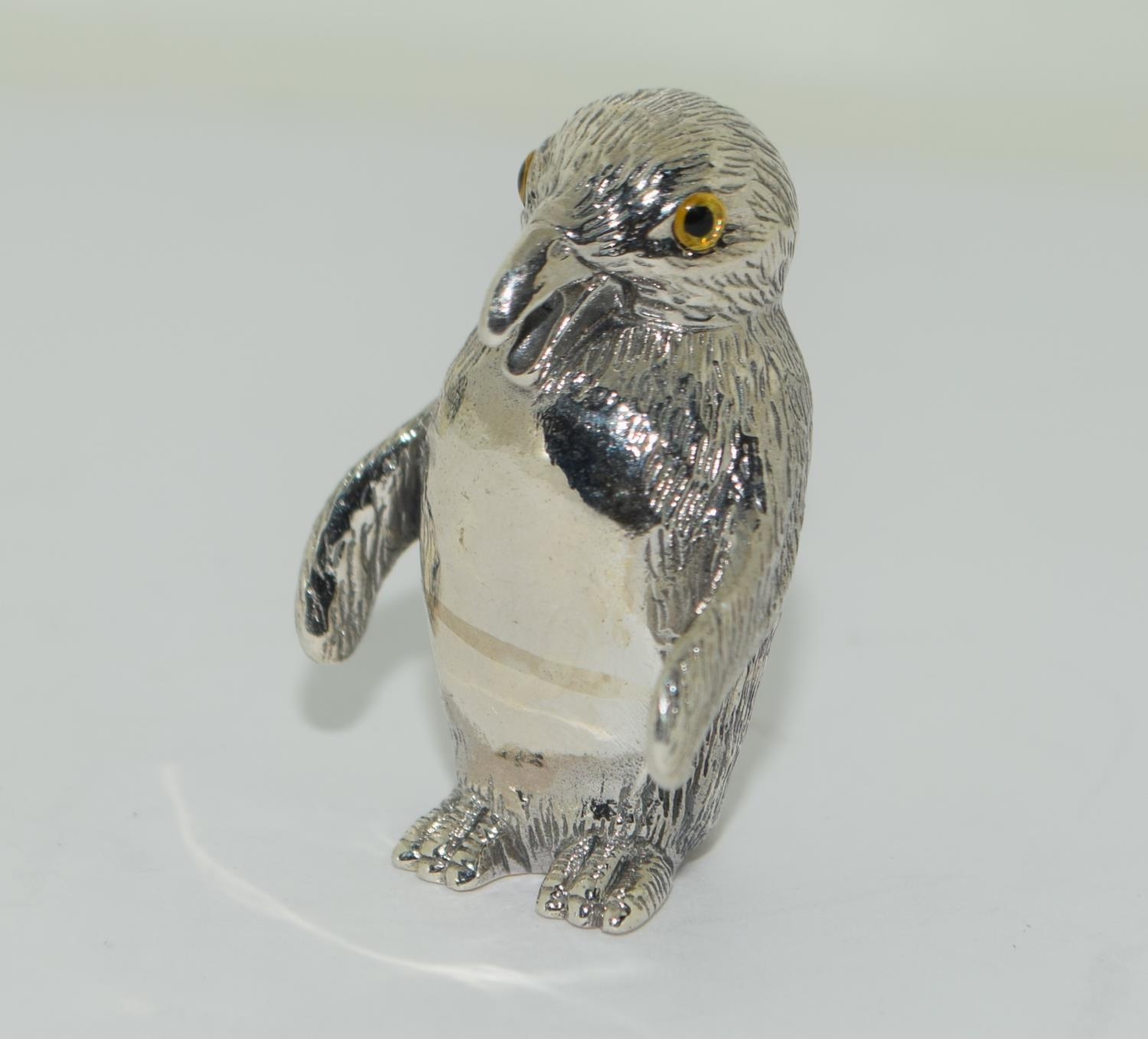 A Silver figure of a penguin.