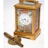 A brass cased miniature carriage clock with porcelain panels and a key.