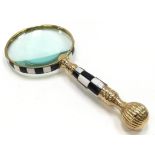 A large brass cased magnifying glass with checkerboard handle.