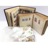 Two vintage stamp albums containing a schoolboy collection of world stamps c/w a large bag of