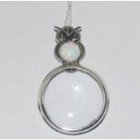 A silver and opal magnifying glass necklace.