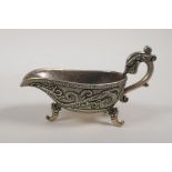 A Chinese white metal libation cup with raised twin dragon decoration and tripod supports, mark to