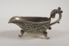 A Chinese white metal libation cup with raised twin dragon decoration and tripod supports, mark to