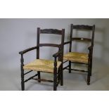A pair of oak elbow chairs with carved back rails and rush seats, raised on turned supports