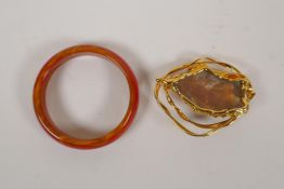 A red banded agate bangle and a gilt metal mounted stone brooch, 3" diameter