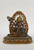 A Sino Tibetan painted bronze figure of a deity seated on a temple lion, impressed 4 character