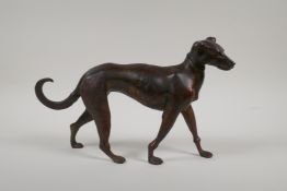 A filled bronze figure of a dog with gilt and coppered patina, 12" long