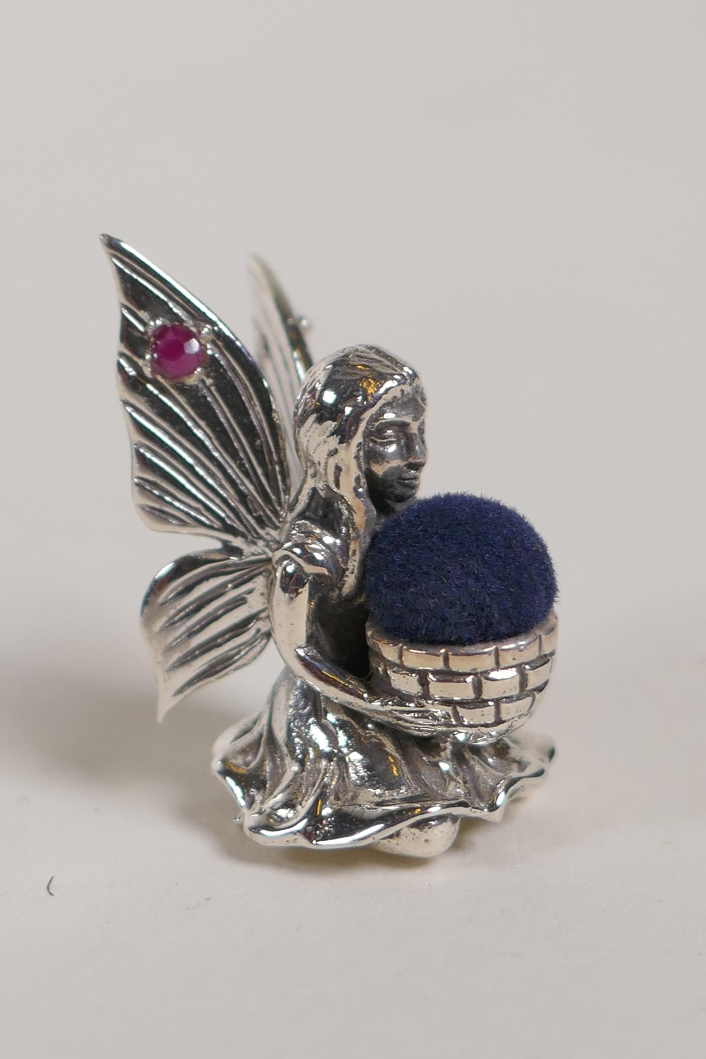 A Sterling silver fairy pincushion with rubies set to the wings, 1" high