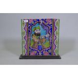 A plaque comprising four ceramic tiles with Persian style decoration depicting a man at prayer,